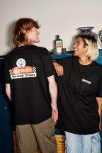 Two people wearing black Jägermeister racing t-shirts with a logo and text, standing close to each other.