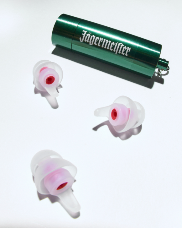 Recipiente verde Jägermeister com três protetores auriculares brancos sobre fundo branco