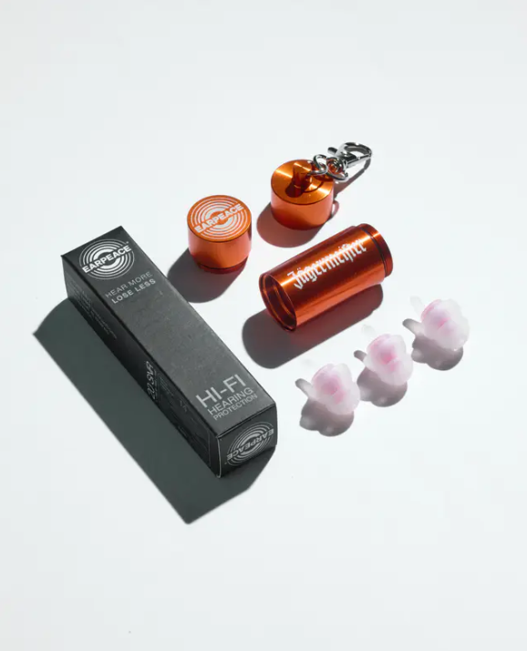 Três protetores auriculares, uma caixa metálica laranja com a marca Jägermeister em branco e uma caixa de embalagem preta sobre fundo branco