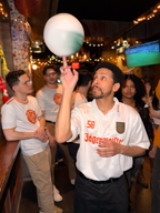 Homem a segurar uma bola colorida num bar, com outras pessoas à volta